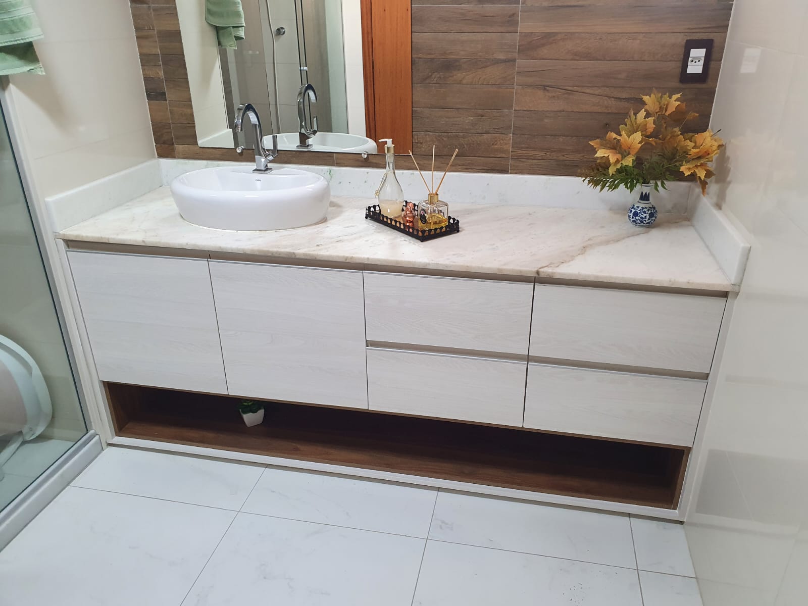 Gabinete de banheiro suspenso em MDF branco com nicho amadeirado, bancada de mármore e cuba de apoio redonda